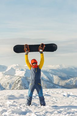 Snowboardcu Freerider kışın karlı dağlarda bulutların altında duruyor.
