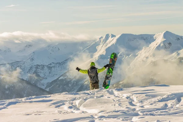 Snowboarder freerider está de pie en las montañas nevadas en invierno bajo las nubes —  Fotos de Stock