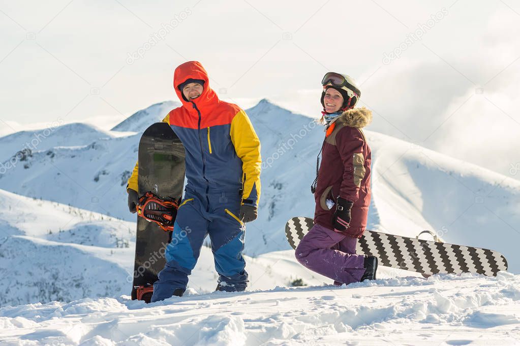 Couple snowboarding freeriders man and a woman go with snowboards on the ridge