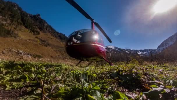 Helicóptero rojo está estacionado en las montañas en el prado — Vídeos de Stock