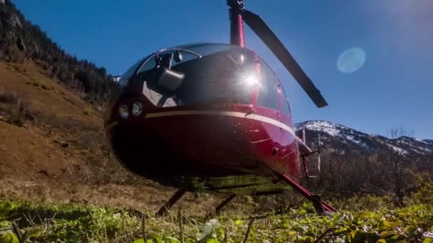 Hélicoptère rouge stationné dans les montagnes sur la prairie — Video