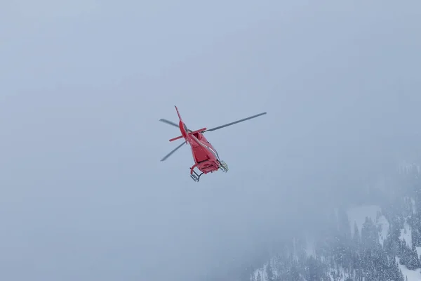 Röd rescue helikopter flyga i snötäckta berg — Stockfoto