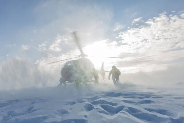 Heliski helicopter takes off in snow powder freeride landed on mountain