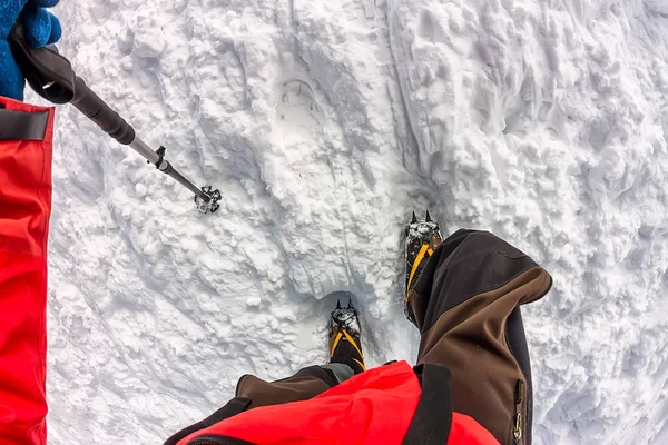 Tied climbers climbing mountain with snow field tied with a rope with ice axes and helmets first person