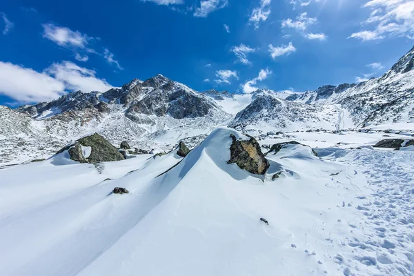 Θέα από την κοιλάδα στην κορυφή του τα χιονισμένα βουνά κάτω από το γαλάζιο του ουρανού — Φωτογραφία Αρχείου