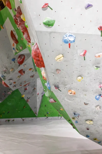 Parede de escalada no salão de pedras com ganchos coloridos — Fotografia de Stock