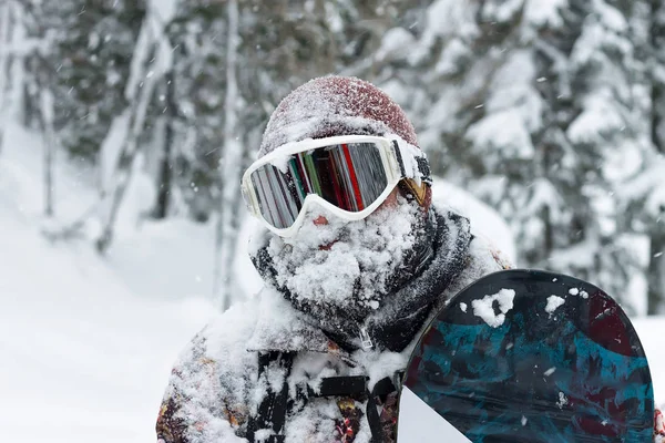 Portrait homme barbu lunettes de ski tenant snowboard dans les montagnes — Photo
