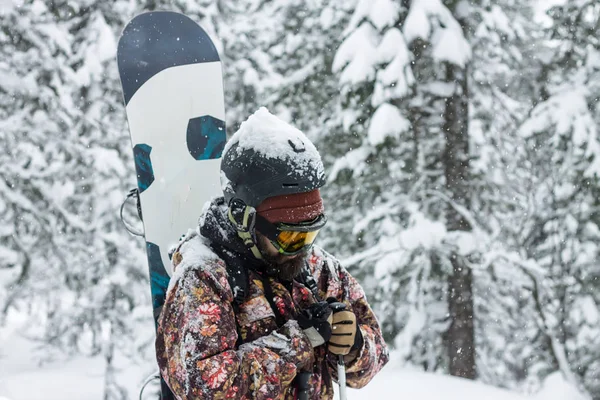 Portrait homme barbu lunettes de ski tenant snowboard dans les montagnes — Photo
