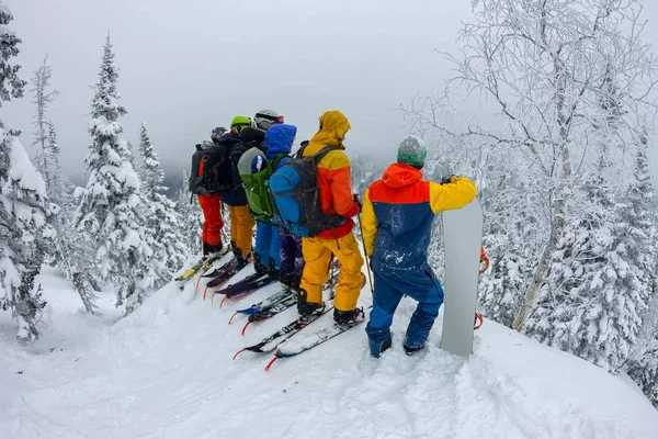 Grupo de esquiadores free-riders, snowboarders de pie en la ladera de la montaña y mirar hacia abajo —  Fotos de Stock