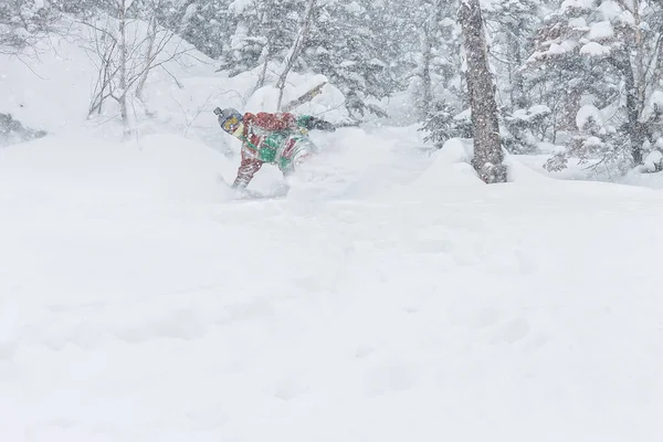 Homem snowboarder freerider vai para baixo na neve em pó nas montanhas em uma queda de neve — Fotografia de Stock