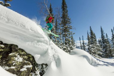Bir rock kar dağlarda ağaçlarda Freerider kayakçı atlar