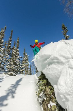 Bir rock kar dağlarda ağaçlarda Freerider kayakçı atlar