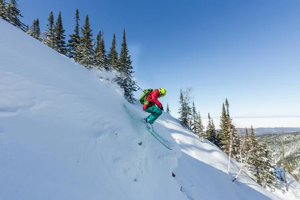 Freerider esquiador salta desde una roca de nieve en los árboles en las montañas — Foto de Stock