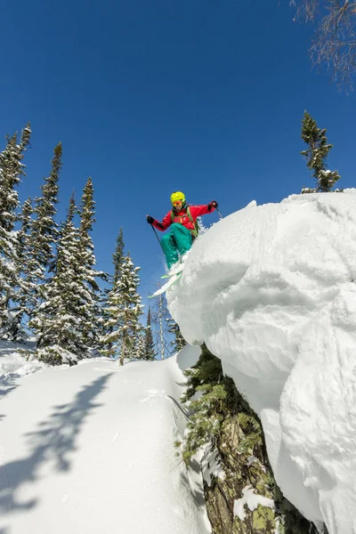 Bir rock kar dağlarda ağaçlarda Freerider kayakçı atlar