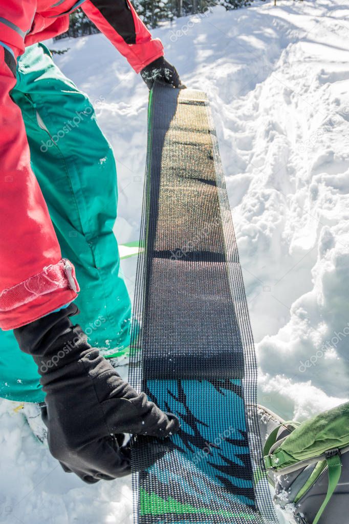 man freerider installs glue camus on skis, in snow wild mountains