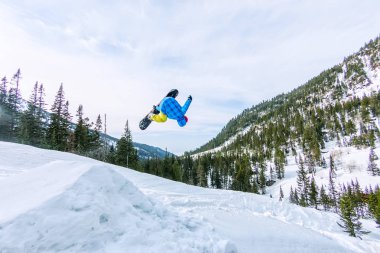 Snowboard freerider orman ve dağlar bir arka plan üzerinde bir kar rampa güneşin üzerinden atlama