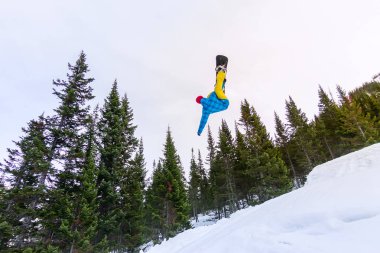 Snowboard freerider orman ve dağlar bir arka plan üzerinde bir kar rampa güneşin üzerinden atlama