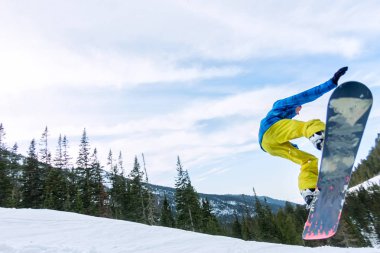 Snowboard freerider orman ve dağlar bir arka plan üzerinde bir kar rampa güneşin üzerinden atlama