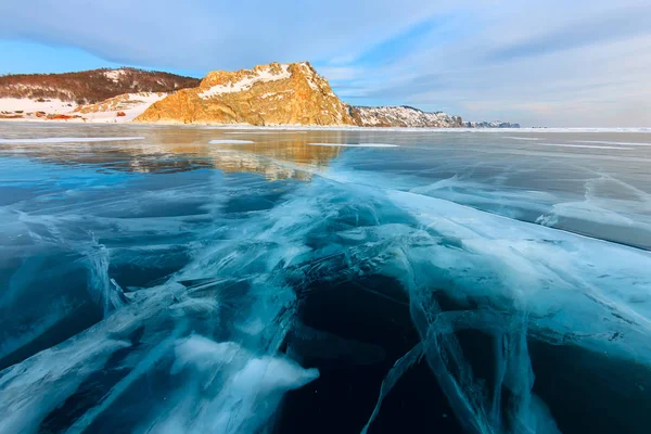 A cruz de fendas profundas no gelo grosso do lago de inverno Baikal em frente à montanha rochosa de Ilha de Olkhon — Fotografia de Stock