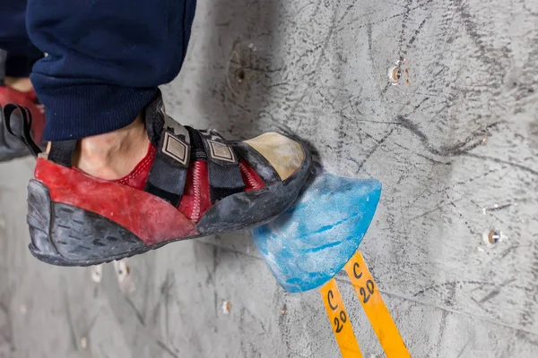 Rocky shoe on a big hook stands with the tip of the sock close up, on the climbing wall in the room — Stock Photo, Image