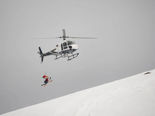 Kayakçı freerider helikopter Heliski'nin karlı dağda atlar.