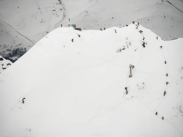 group of freeriders snowboarders skiers rises uphill in the Caucasus in the rose khutor