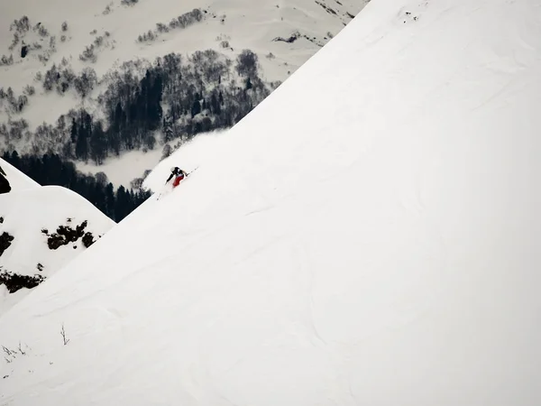 Freerider skiër daalt een steile helling van witte sneeuw en bomen in de bergen van de Kaukasus — Stockfoto