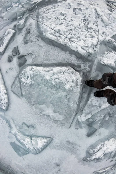 Человеческие ноги в походном сапоге в ледяных костылях на текстуре Байкальского льда — стоковое фото