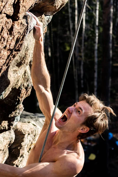 Rock-climber man screaming for tension holding on to a rock with one hand, close-up — Stock Photo, Image