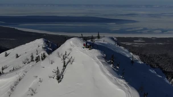 Aeronave de freeriders de equipe de drone que se preparam nas montanhas nevadas para cima em uma linha — Vídeo de Stock