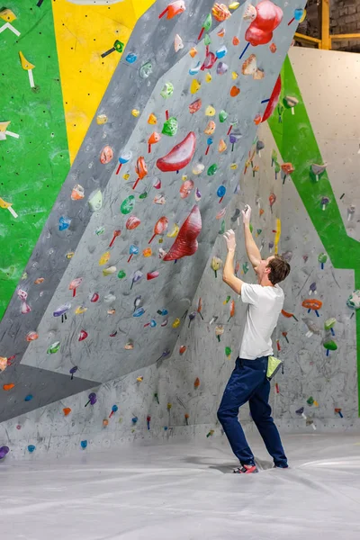 Escalador explora y desarrolla una ruta en un muro de escalada en la sala de rocas —  Fotos de Stock