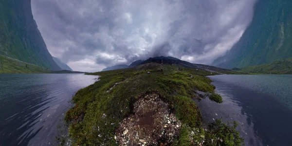 Montagnes noires dans les nuages de pluie, le pied couvert de pierres et d'herbe verte. Panorama grand angle — Photo
