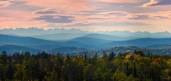 Ángulo amplio panorama bosque otoñal, colinas brumosas cumbres montañosas en rosa amanecer — Foto de Stock
