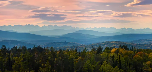 Wide angle panorama autumn forest,misty hills mountain tops in pink dawn