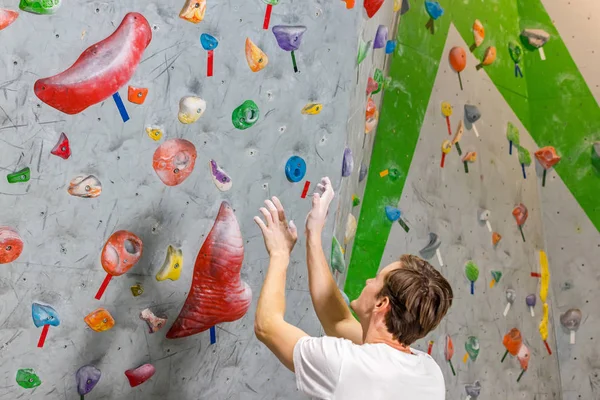 Escalador explora y desarrolla una ruta en un muro de escalada en la sala de rocas —  Fotos de Stock