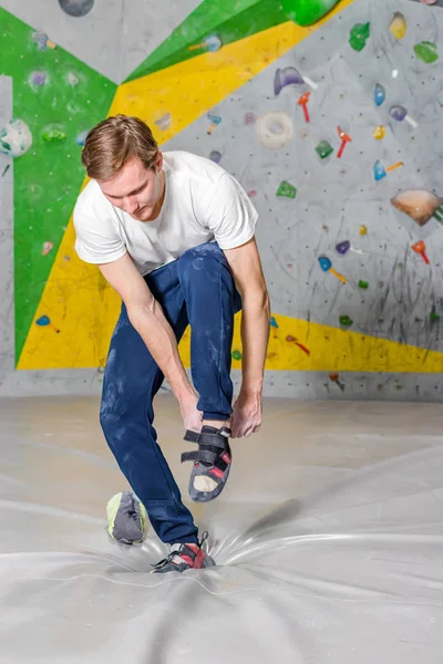 Rock climber puts on rocky shoes in a bouldering hall at a climbing gym — Stock Photo, Image