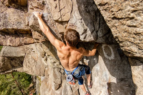 Climber Extreme climbs a rock on a rope with the top insurance, overlooking the forest — Stock Photo, Image