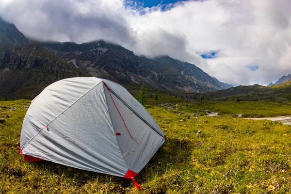 Tente grise se dresse dans une prairie dans les montagnes près du lac dans un orage — Photo