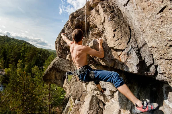 Climber Extreme climbs a rock on a rope with the top insurance, overlooking the forest — Stock Photo, Image