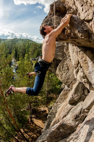 Extremkletterer erklimmt einen Felsen an einem Seil mit der Top-Versicherung, mit Blick auf den Wald — Stockfoto