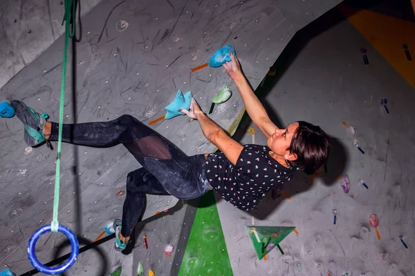 Mujer escaladora colgando en una pared de escalada de cantos rodados, dentro de ganchos de colores —  Fotos de Stock