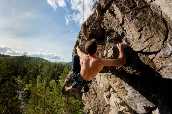 Extremkletterer erklimmt einen Felsen an einem Seil mit der Top-Versicherung, mit Blick auf den Wald — Stockfoto