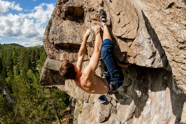 Extremkletterer erklimmt einen Felsen an einem Seil mit der Top-Versicherung, mit Blick auf den Wald — Stockfoto