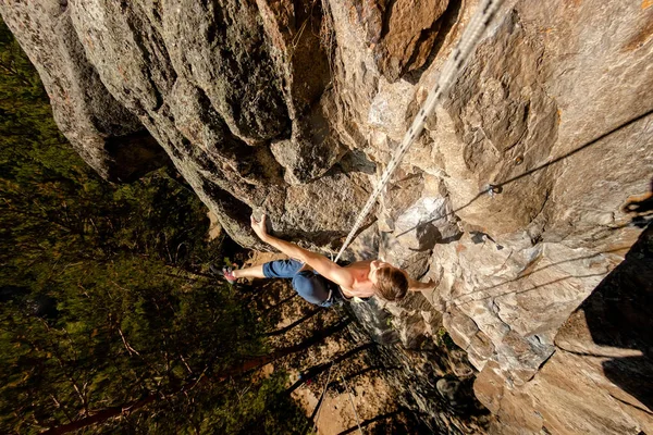 Extremkletterer besteigt einen Felsen an einem Seil mit der Top-Versicherung, Blick von oben — Stockfoto