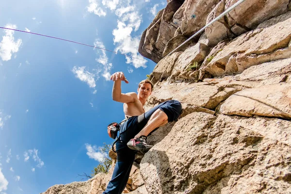 Top mavi gökyüzü, alt görünümü karşı sigorta ile bir ip üzerinde bir kaya tırmanma aşırı tırmanıyor — Stok fotoğraf