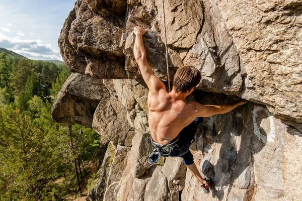 Climber Extreme climbs a rock on a rope with the top insurance, overlooking the forest — Stock Photo, Image