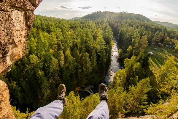 Klimmers benen hangen aan een touw in een harnas, eerste persoonsmening rivier in bos — Stockfoto