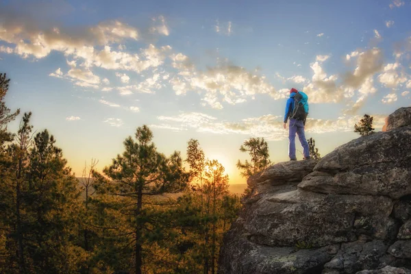 Hiker with backpack standing on a rock and enjoying sunset on mauntain — Stock Photo, Image