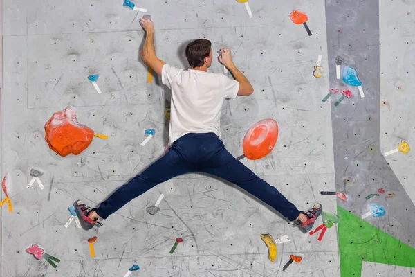 Horolezec muž visí v vlákna na lezeckou stěnu boulderingu zdi, na barevné háčky — Stock fotografie