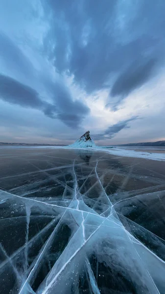 Gelo do Lago Baikal em rachaduras perto da ilha de Elenka ao pôr do sol sob nuvens cinzas. Panorama amplo — Fotografia de Stock